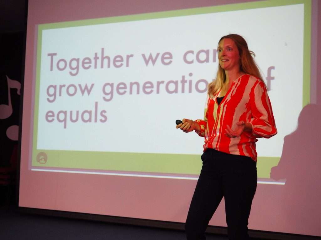 Clare in orange top presenting on stage
